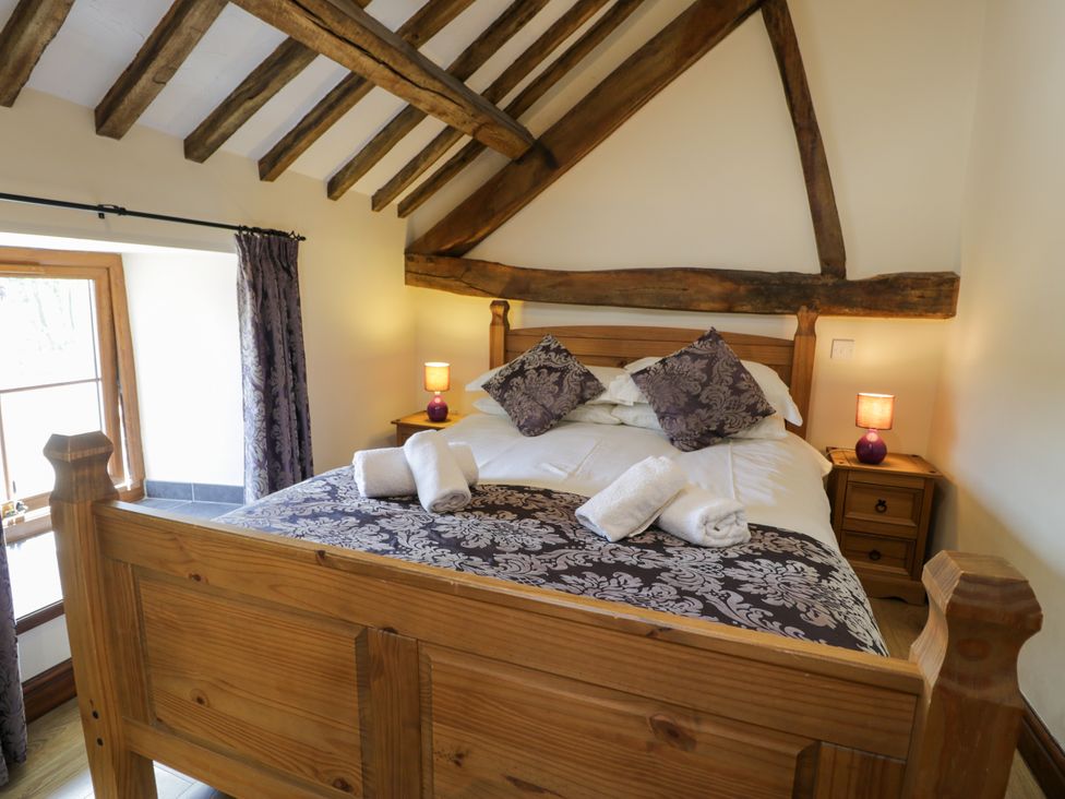 A bedroom with a wooden bed and bedside table at Bwthyn Y Wennol Dolwen near Abergele