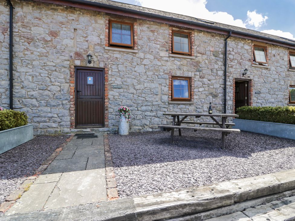 An outdoor area with a stone wall and picnic table at Bwthyn Y Wennol Dolwen near Abergele