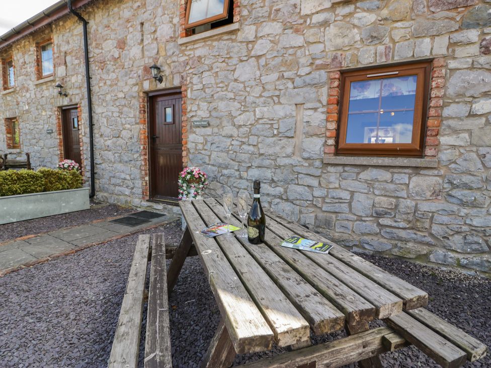 A table with a bottle and brochures at Bwthyn Y Wennol in Dolwen near Abergele