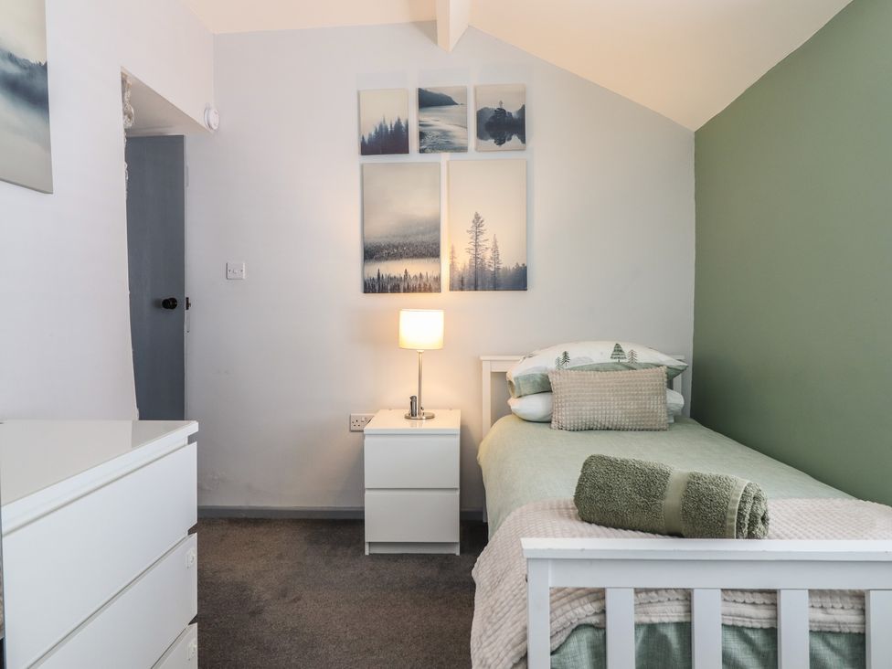 A bedroom with a single bed and nightstand at Arthur’s Cottage Abergynolwyn near Tywyn