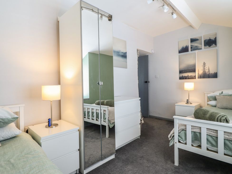 A bedroom with beds, lamps, and a closet at Arthur’s Cottage in Abergynolwyn near Tywyn