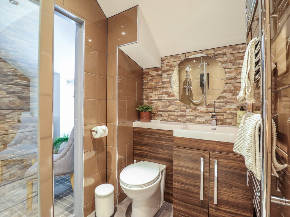 A bathroom with a shower, toilet, sink and mirror at Arthur’s Cottage Abergynolwyn near Tywyn