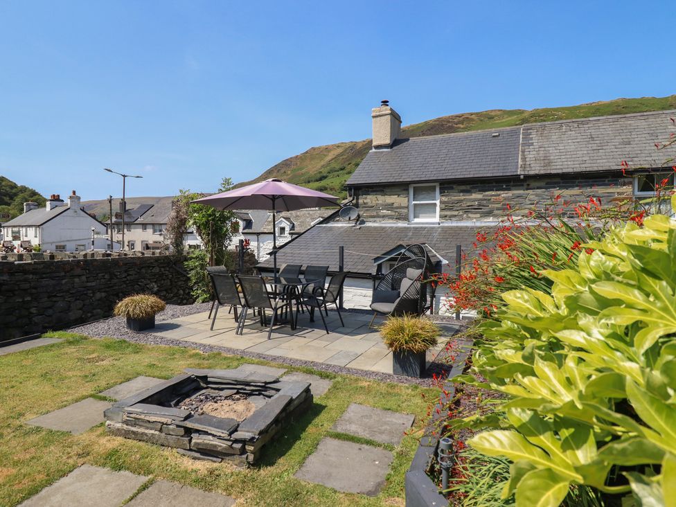 A garden with a dining set and fire pit at Arthur’s Cottage Abergynolwyn near Tywyn