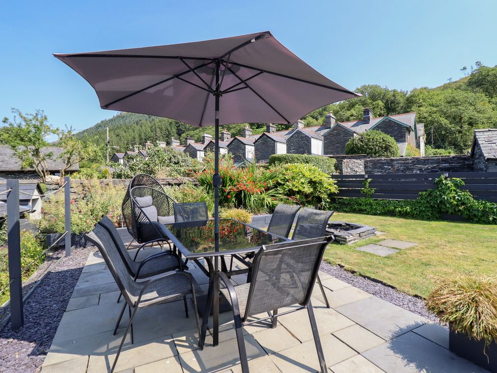 A garden with a table and chairs under an umbrella at Arthur’s Cottage in Abergynolwyn near Tywyn