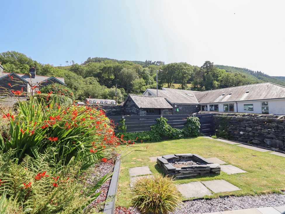 A garden with a fire pit and flowerbed at Arthur’s Cottage in Abergynolwyn near Tywyn