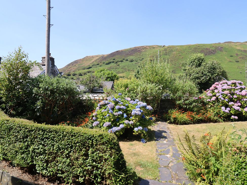 A garden with flowers and a pathway at Arthur’s Cottage in Abergynolwyn near Tywyn