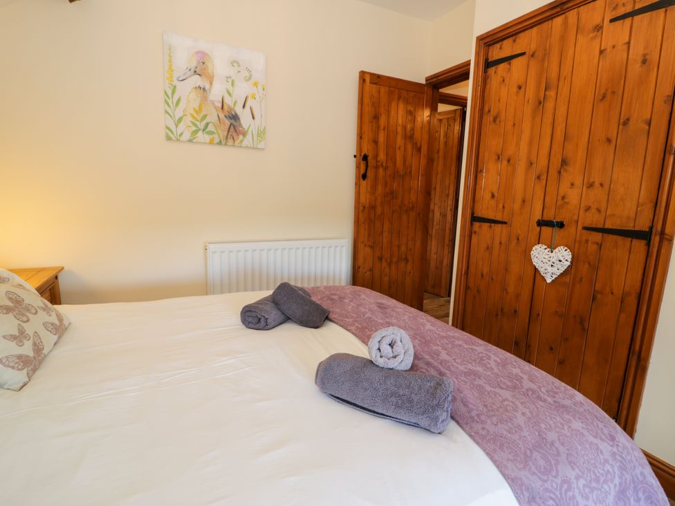 A bedroom with towels on a bed and a painting on the wall at Cornel Clyd in Dolwen near Abergele