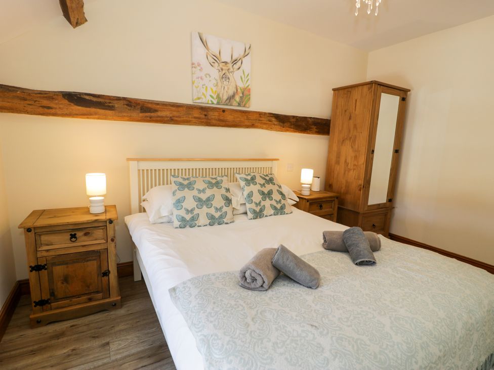 A bedroom with a bed, nightstand, and wardrobe at Cornel Clyd, Dolwen near Abergele