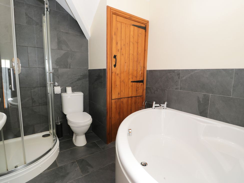 A bathroom with a shower, toilet and bathtub at Cornel Clyd in Dolwen near Abergele