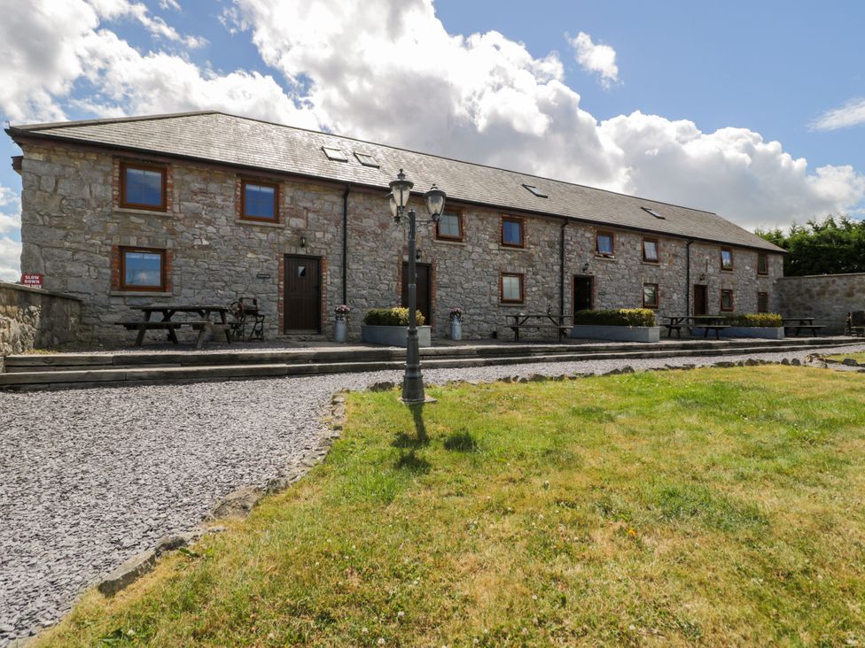 An outdoor area with a stone building and picnic tables at Cornel Clyd Dolwen near Abergele