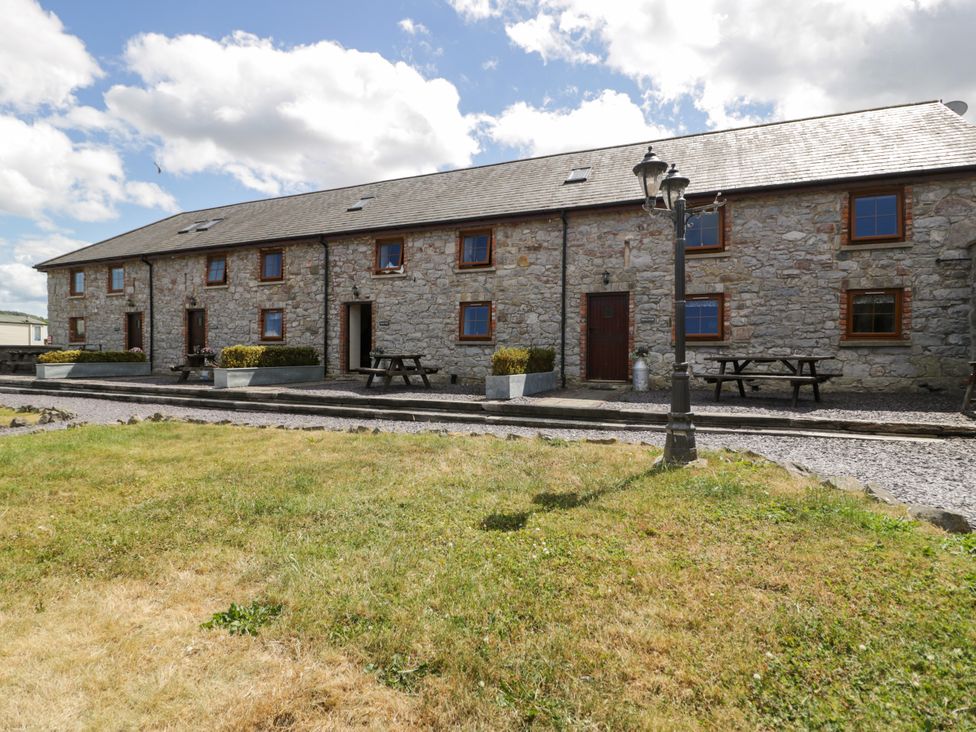 A stone building with windows and doors in a garden at Cornel Clyd Dolwen near Abergele