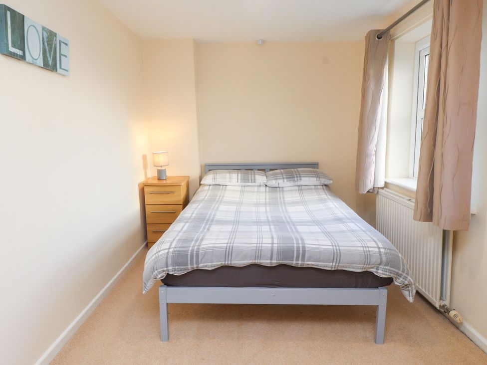 A bedroom with a bed and nightstand at Pant Fali in Aberdaron