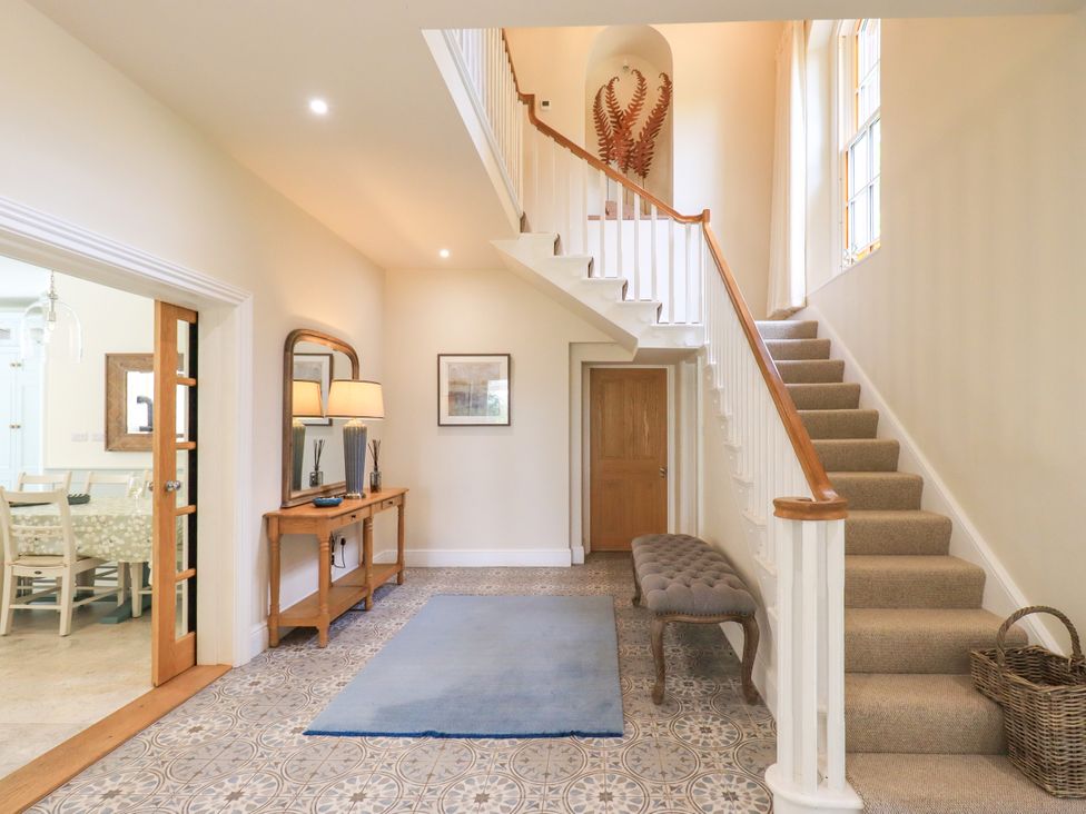 A hallway with a staircase and console table at Fern Bank in Penrith