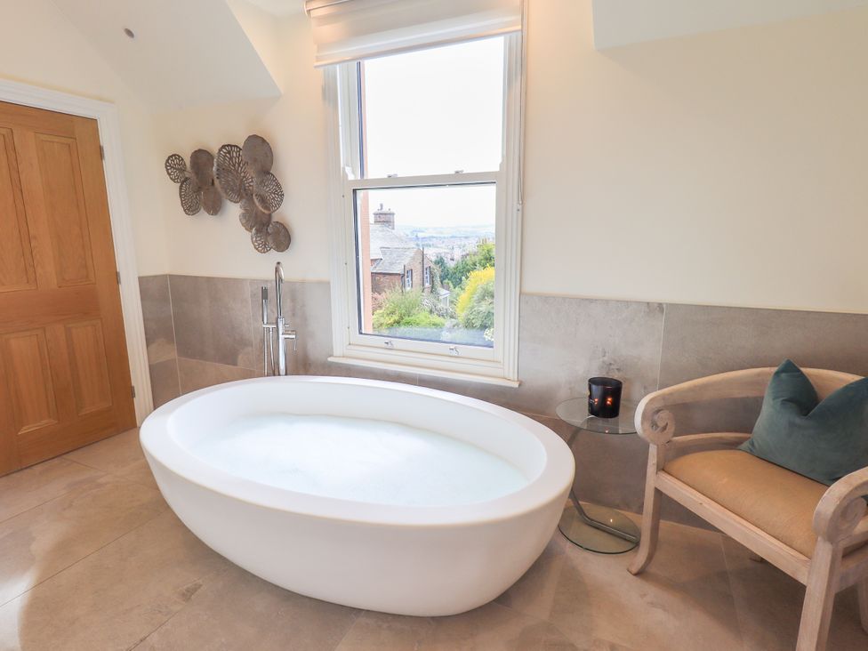 A bathroom with a bathtub and a chair at Fern Bank in Penrith