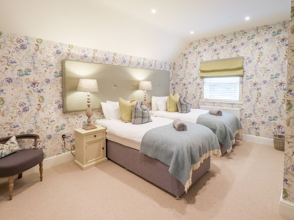 A bedroom with twin beds and decorative wallpaper at Fern Bank in Penrith