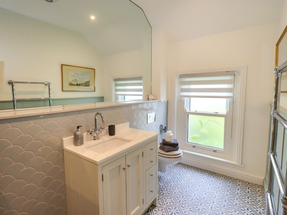 A bathroom with a sink, toilet, and mirror at Fern Bank in Penrith