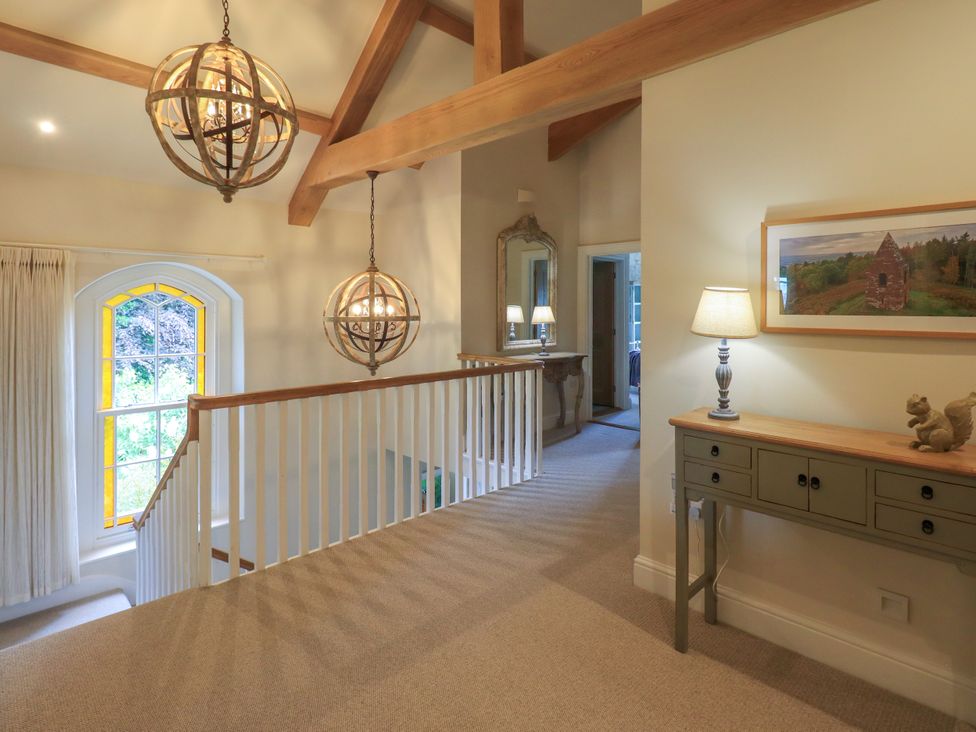 A hallway with a chandelier and mirrored table at Fern Bank in Penrith