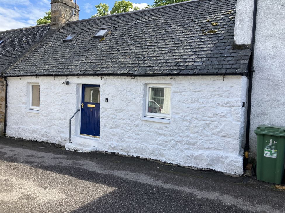 A white cottage with a blue door and windows at 3 Dunrobin Street Tain