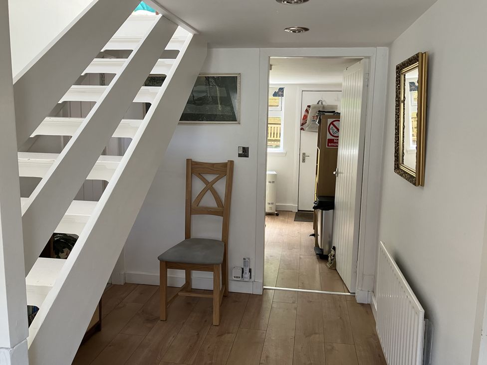 A hallway with a staircase and chair at 3 Dunrobin Street Tain