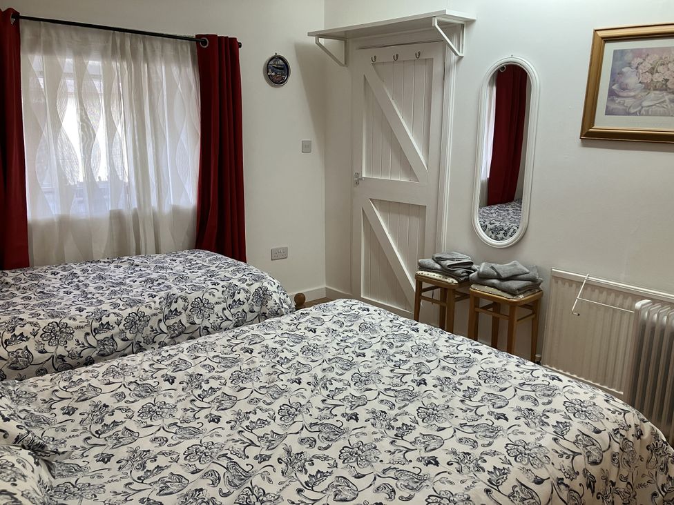 A bedroom with two beds and a mirror at 3 Dunrobin Street Tain