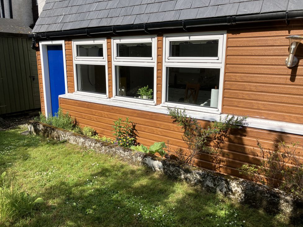 An outdoor view of a wooden exterior with windows and a blue door at 3 Dunrobin Street Tain