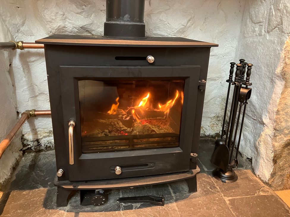 A wood stove with fire in a living room at 3 Dunrobin Street Tain