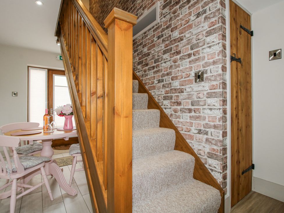 A dining area with a staircase and a table at Meadow Barn in Aston On Clun
