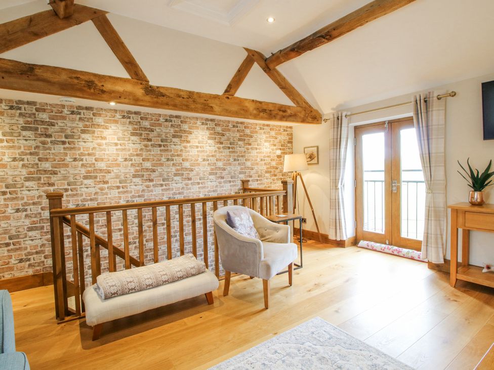 A living room with a brick wall and wooden beams at Meadow Barn Aston On Clun