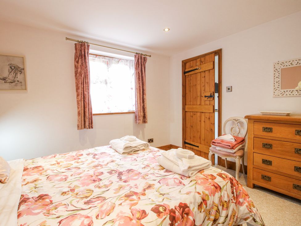 A bedroom with a bed and wooden furniture at Meadow Barn Aston On Clun