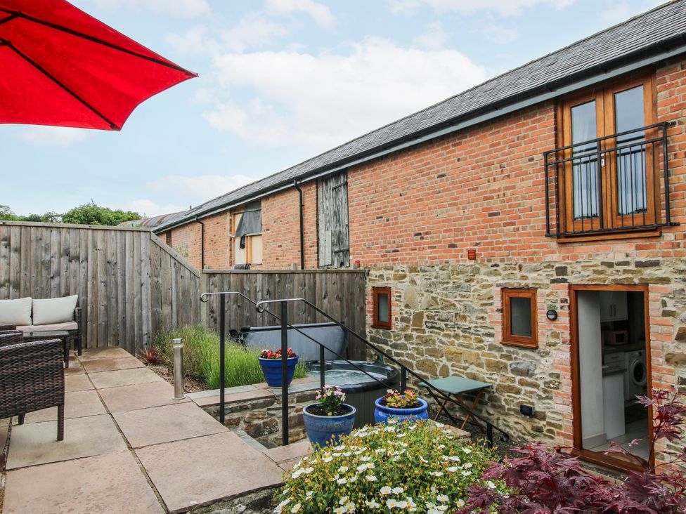 An outdoor area with a hot tub and seating at Meadow Barn Aston On Clun