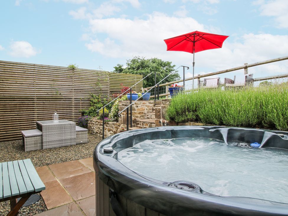 A garden with a hot tub and outdoor seating at Meadow Barn in Aston On Clun