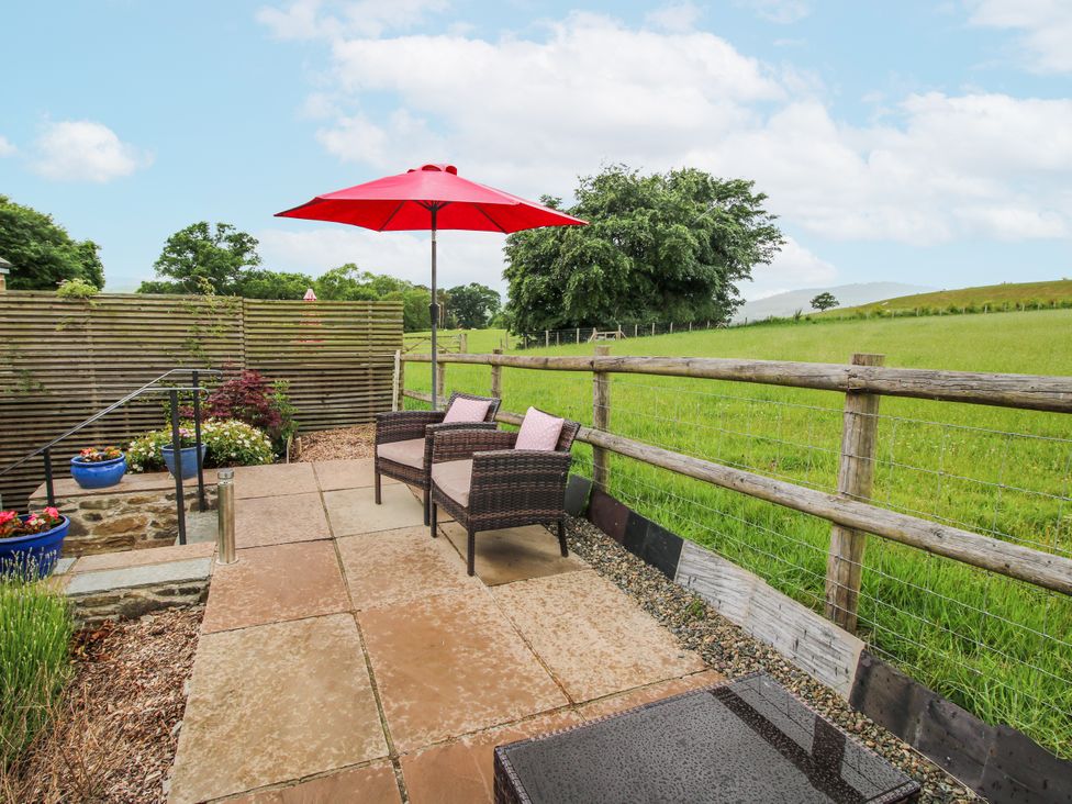 An outdoor area with chairs and an umbrella at Meadow Barn Aston On Clun
