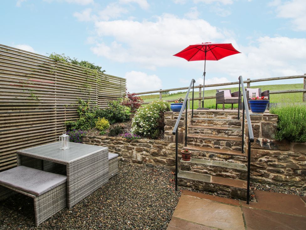 An outdoor seating area with a table and chairs at Meadow Barn Aston On Clun