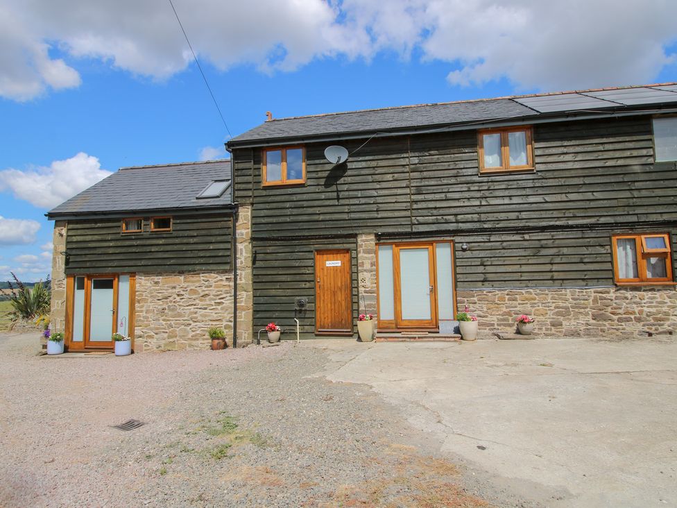 A house with stone wall and wooden paneling at Meadow Barn Aston On Clun