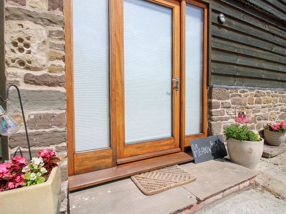 An entrance with wooden door and planters at Meadow Barn Aston On Clun