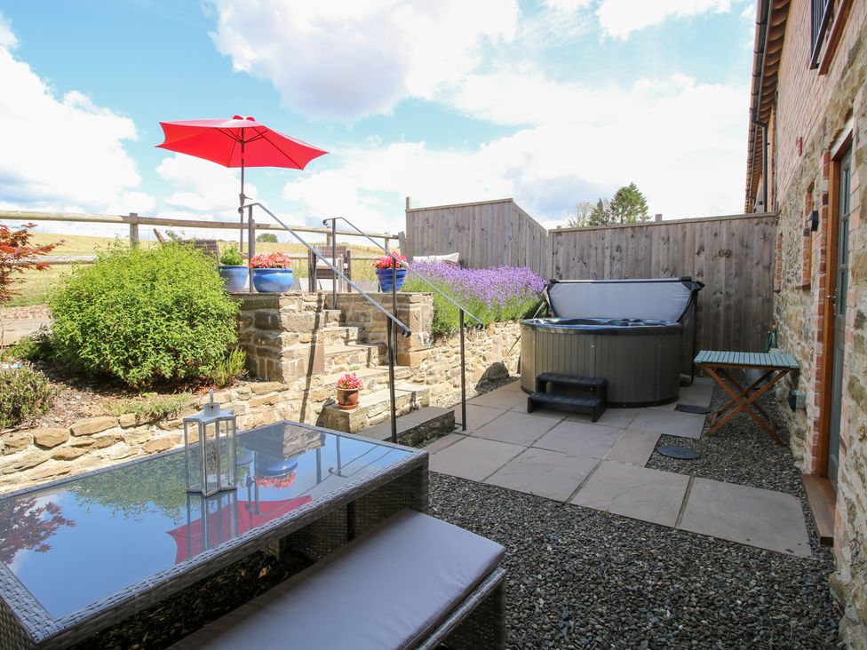 A garden with a hot tub and outdoor seating area at Meadow Barn Aston On Clun