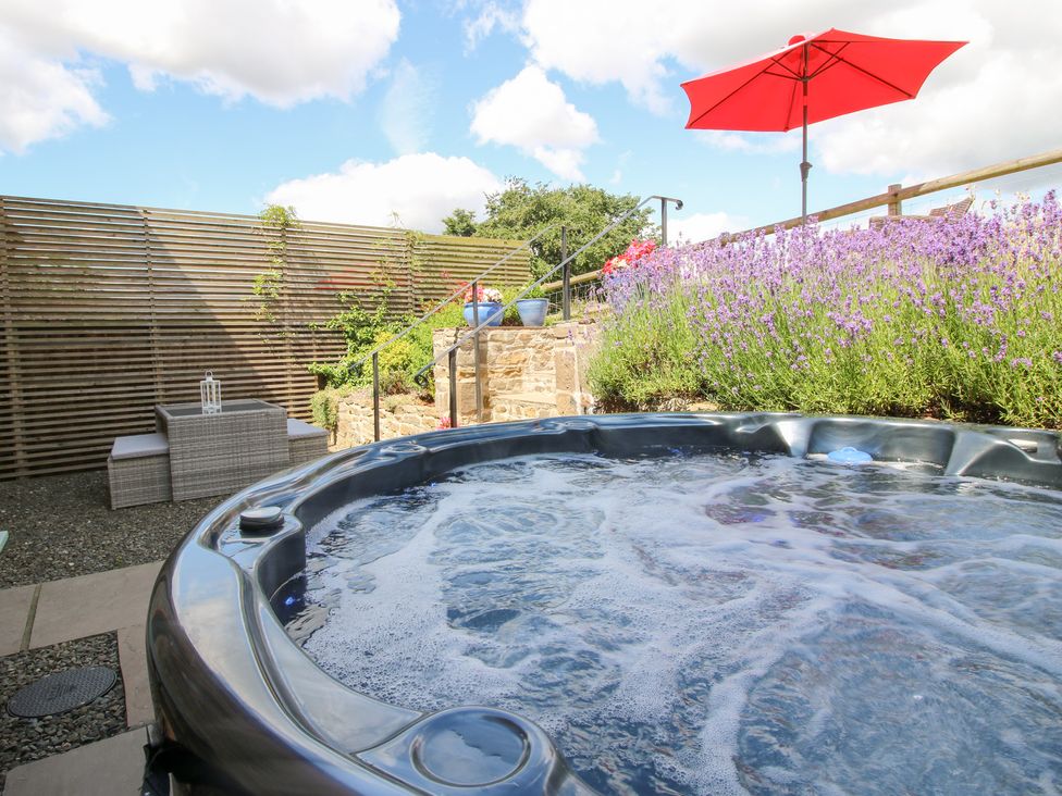 An outdoor area with a hot tub and seating at Meadow Barn Aston On Clun