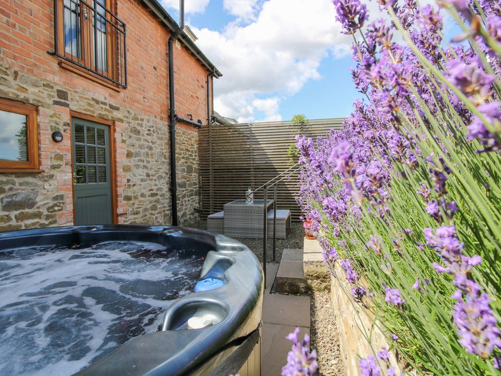 An outdoor area with a hot tub and lavender flowers at Meadow Barn Aston On Clun
