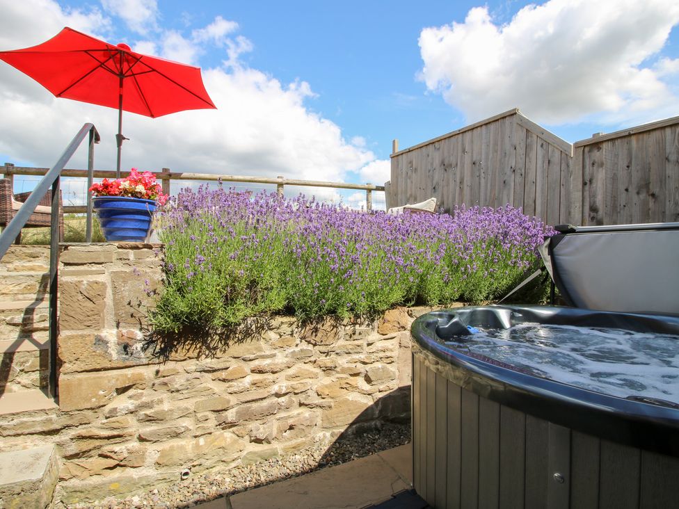 An outdoor garden with a jacuzzi and lavender plants at Meadow Barn Aston On Clun