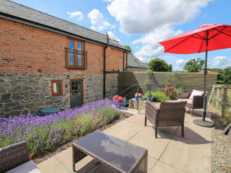 An outdoor seating area with furniture and lavender plants at Meadow Barn Aston On Clun