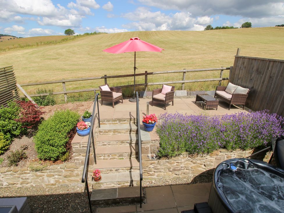 An outdoor area with seating, steps, and flowers at Meadow Barn Aston On Clun