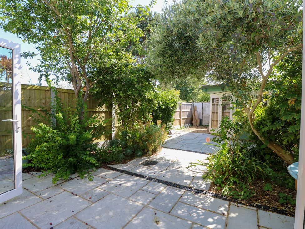 A garden with paving stones, trees, bushes and a shed at Merrilees in Yarmouth