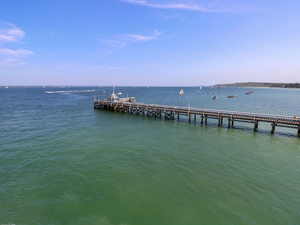 A pier extending into water with boats sailing in the distance at Merrilees in Yarmouth