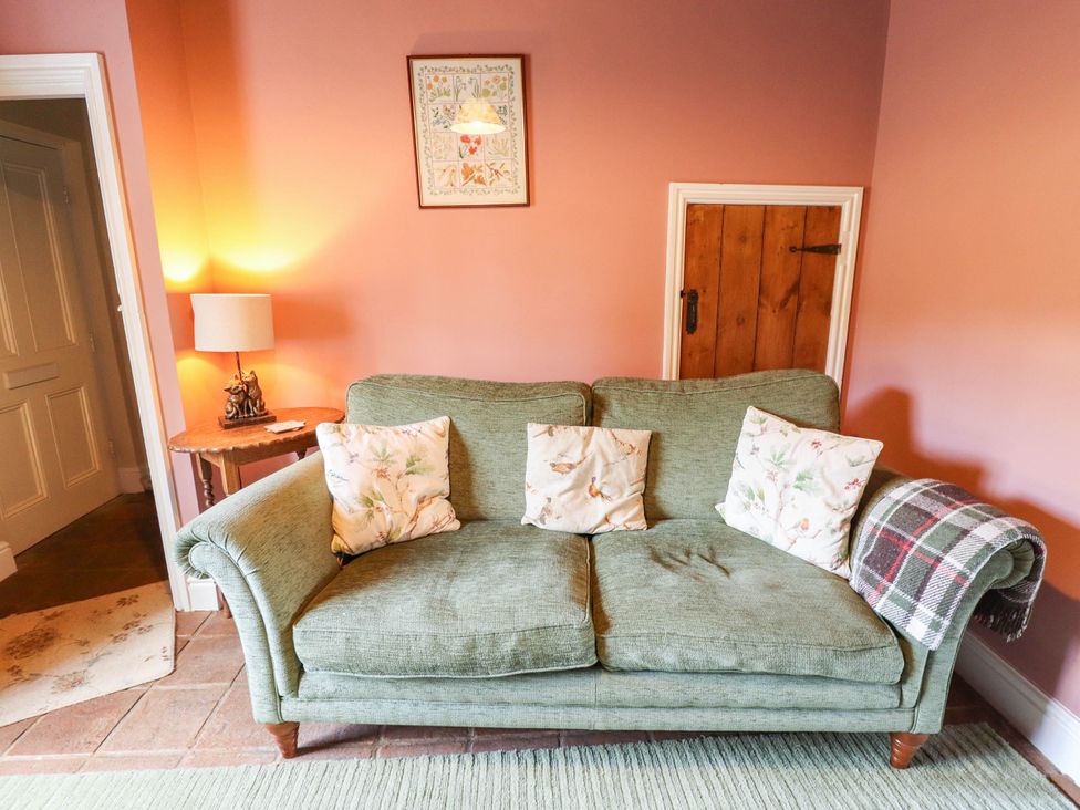 A living room with a sofa and lamp at Marmaduke Cottage in Market Weighton