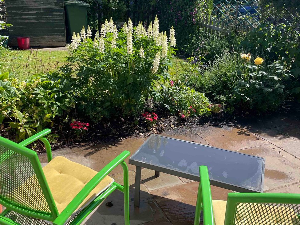 A garden with green chairs and a glass table at Marmaduke Cottage in Market Weighton