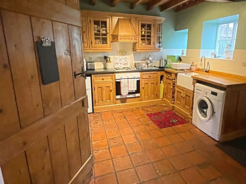A kitchen with wooden cabinets and a washing machine at Marmaduke Cottage in Market Weighton