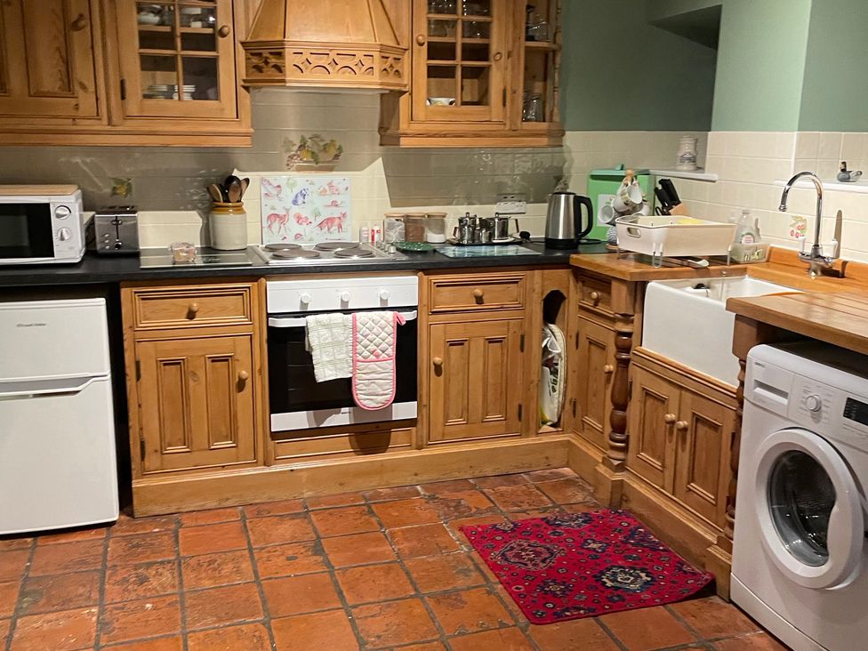 A kitchen with wooden cabinets and appliances at Marmaduke Cottage in Market Weighton