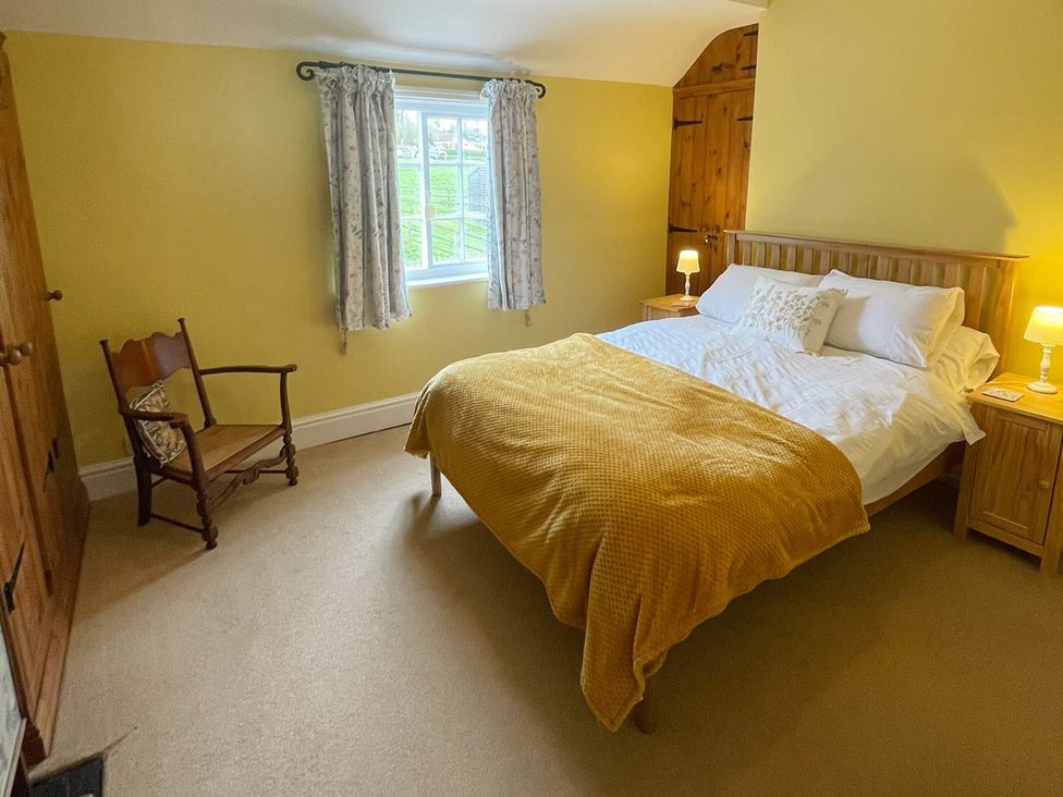 A bedroom with a bed and a rocking chair at Marmaduke Cottage in Market Weighton