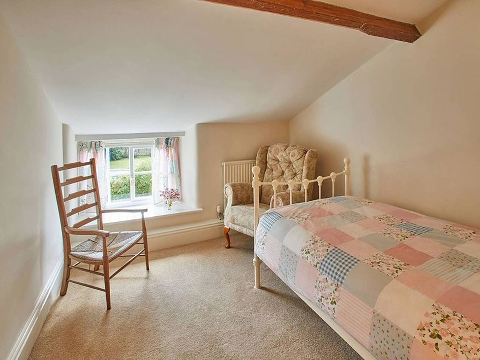 A bedroom with a bed and a chair at Marmaduke Cottage in Sancton near Market Weighton