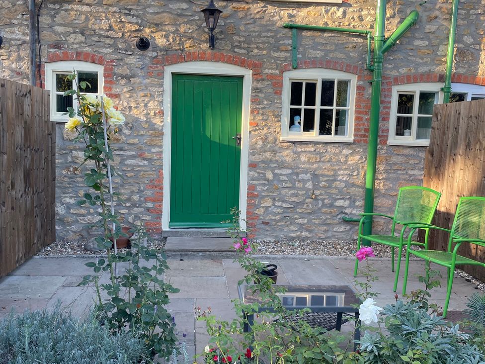 A garden with a green door and flower plants at Marmaduke Cottage Sancton near Market Weighton